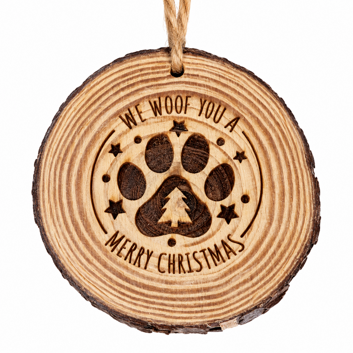 A round wooden Christmas ornament with a natural bark edge, featuring a laser-engraved paw print with a small Christmas tree in the center, surrounded by the text 'WE WOOF YOU A' and 'MERRY CHRISTMAS'. The ornament hangs from a natural jute string against a solid white background.