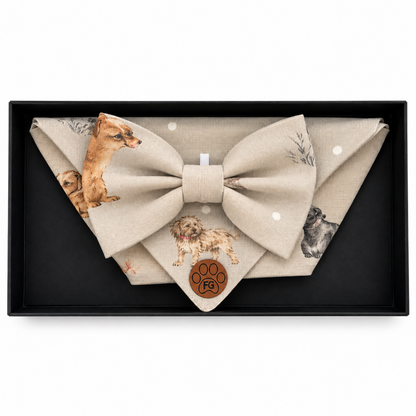 A beige fabric bow tie and matching pocket square set with dog illustrations, presented in a black gift box. The pocket square features a brown paw print with the brand name 'Paw Design' inside it.