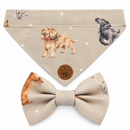 A pet accessory set featuring a beige bandana with dog illustrations and a matching beige bow tie, both printed with a subtle botanical pattern. The bandana has a small brown paw-print patch with a game controller design in the center.
