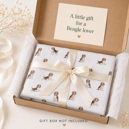 A folded gift box wrapped in white paper printed with small Beagle dog scarf, tied with a cream satin ribbon and presented in an open kraft gift box. A card inside reads 'A little gift for a Beagle lover.