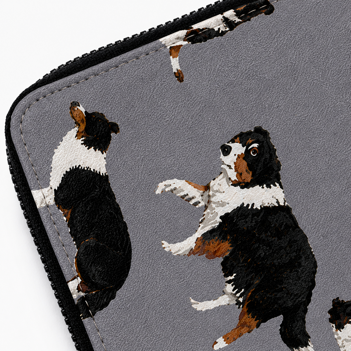 Close-up of a grey zippered sleeve or pouch with a printed pattern of black, white, and brown Border Collie dogs, shown against a white background.