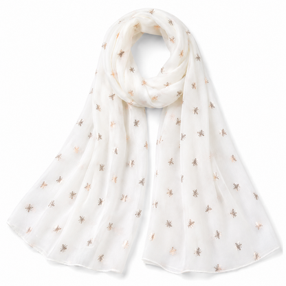 A lightweight white scarf with a delicate pattern of small metallic gold bumblebees, draped elegantly on a clean white background.