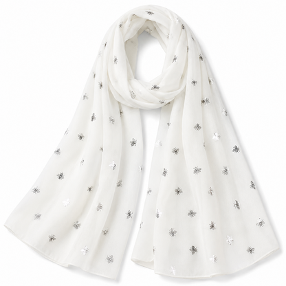 A lightweight white scarf with scattered silver embroidered bumblebee motifs, draped elegantly against a plain white background.