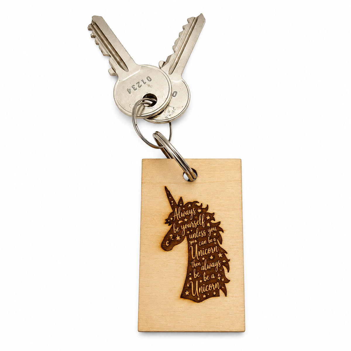A wooden rectangular keychain with a laser-engraved unicorn silhouette and quote, attached to a split ring with two metal keys on a white background.