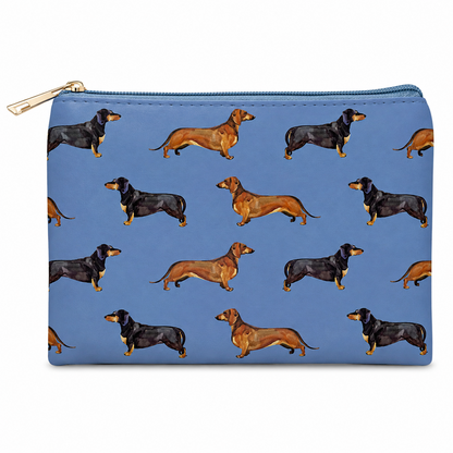 A blue zipped cosmetic bag featuring a repeating pattern of dachshund dogs in black and tan, with a gold zipper pull, shown on a plain white background.