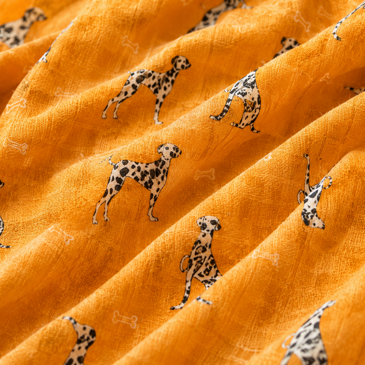 A close-up of textured orange scarf with a repeating pattern of black-and-white Dalmatian dogs and small white bone motifs.