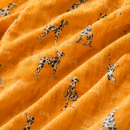 A close-up of textured orange scarf with a repeating pattern of black-and-white Dalmatian dogs and small white bone motifs.