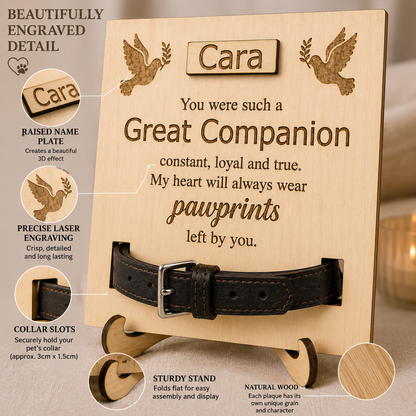 Personalised wooden paw print plaque engraved with a memorial message for 'Cara', shown with a black leather pet collar inserted into the collar slots at the bottom. The image includes callout circles highlighting engraved details, the raised name plate, laser engraving, collar slots, the sturdy stand, and the natural wood grain.