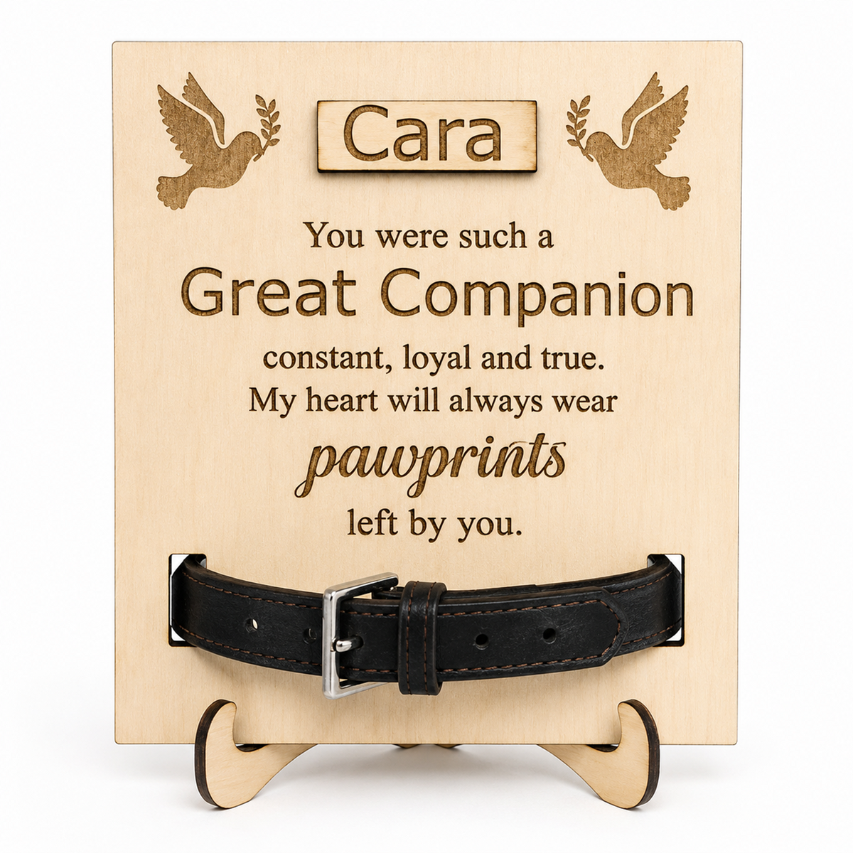 Personalised wooden pet memorial plaque on a small wooden stand, engraved with the name Cara and a pawprint-themed remembrance message, with a black leather collar displayed across the front.