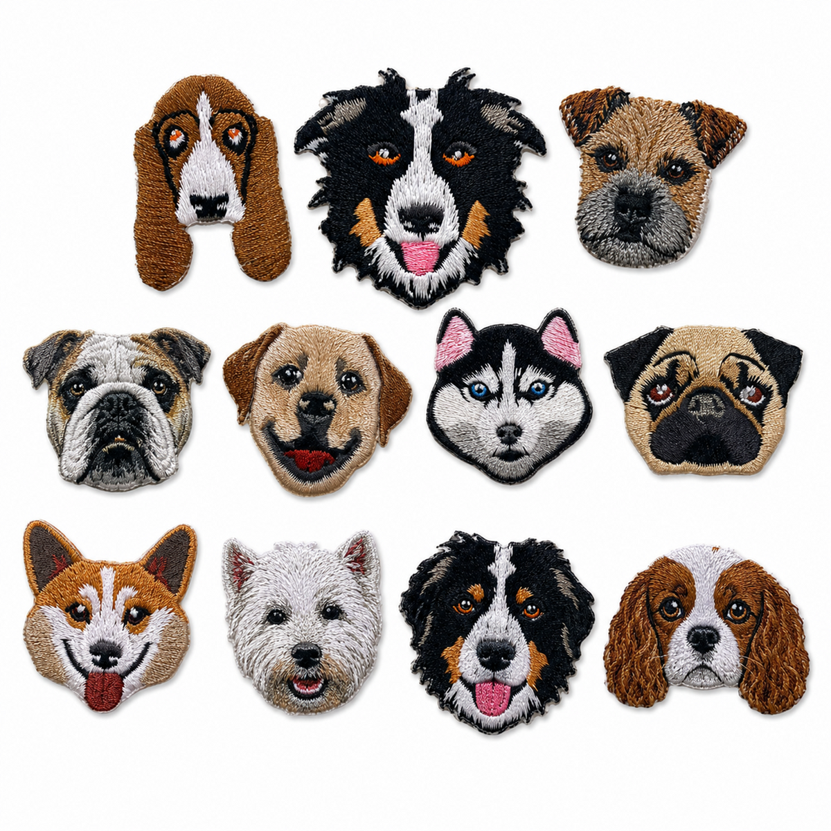 A set of eleven embroidered dog head patches arranged in a 3x4 grid on a plain white background. The patches depict various real dog breeds, including breeds like the Basset Hound, Border Collie, Pug, and Cavalier King Charles Spaniel, in a traditional tufted needlepoint style.