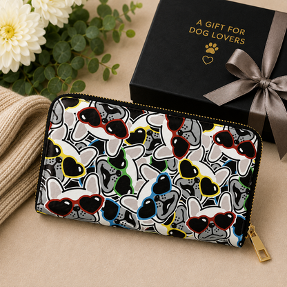 A zip-around wallet with a colourful pattern of cartoon French Bulldog  faces wearing heart-shaped sunglasses, styled next to a black gift box with the text 'A GIFT FOR DOG LOVERS' on a beige background.