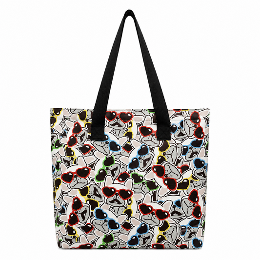 A tote bag with black shoulder straps, featuring a dense cartoon graphic print of stylised French Bulldog faces wearing red, black, blue, green, and yellow sunglasses on a light background.
