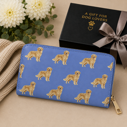 A blue zip-around wallet with a repeating print of golden retriever dogs, styled on a beige surface with a black gift box, flowers, and a cream knit sweater.