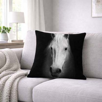 A square cushion cover featuring a high-contrast black and white horse portrait, resting on a light gray sofa in a bright, modern living room.
