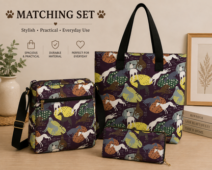 A matching set of three Greyhound Whippet dog-themed tote and crossbody bags displayed on a tabletop with decorative props. The set includes a large tote bag, a medium crossbody bag, and a small zip pouch, all featuring a dark purple background with a whimsical print of dogs in yellow, green, brown, and white, along with trees and foliage.