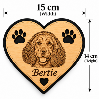Heart-shaped wooden plaque with a engraved dog portrait, two paw prints, and the name 'Bertie' on a light wood surface with black border, shown with dimension arrows labeled 15 cm width and 14 cm height.