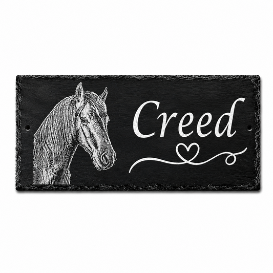 A rectangular black slate sign featuring a white engraved horse head on the left and the name 'Creed' in white script on the right, shown against a plain white background.