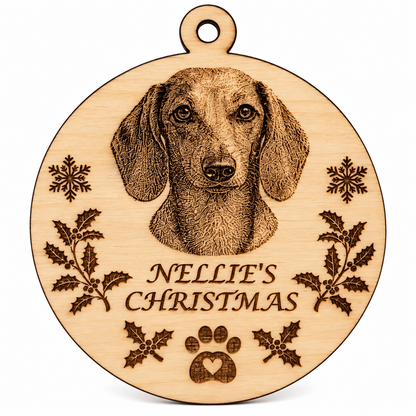 A round wooden pet memorial plaque engraved with a dachshund portrait, the text 'NELLIE'S CHRISTMAS', holly leaves, snowflakes, and a paw print, shown on a white background.