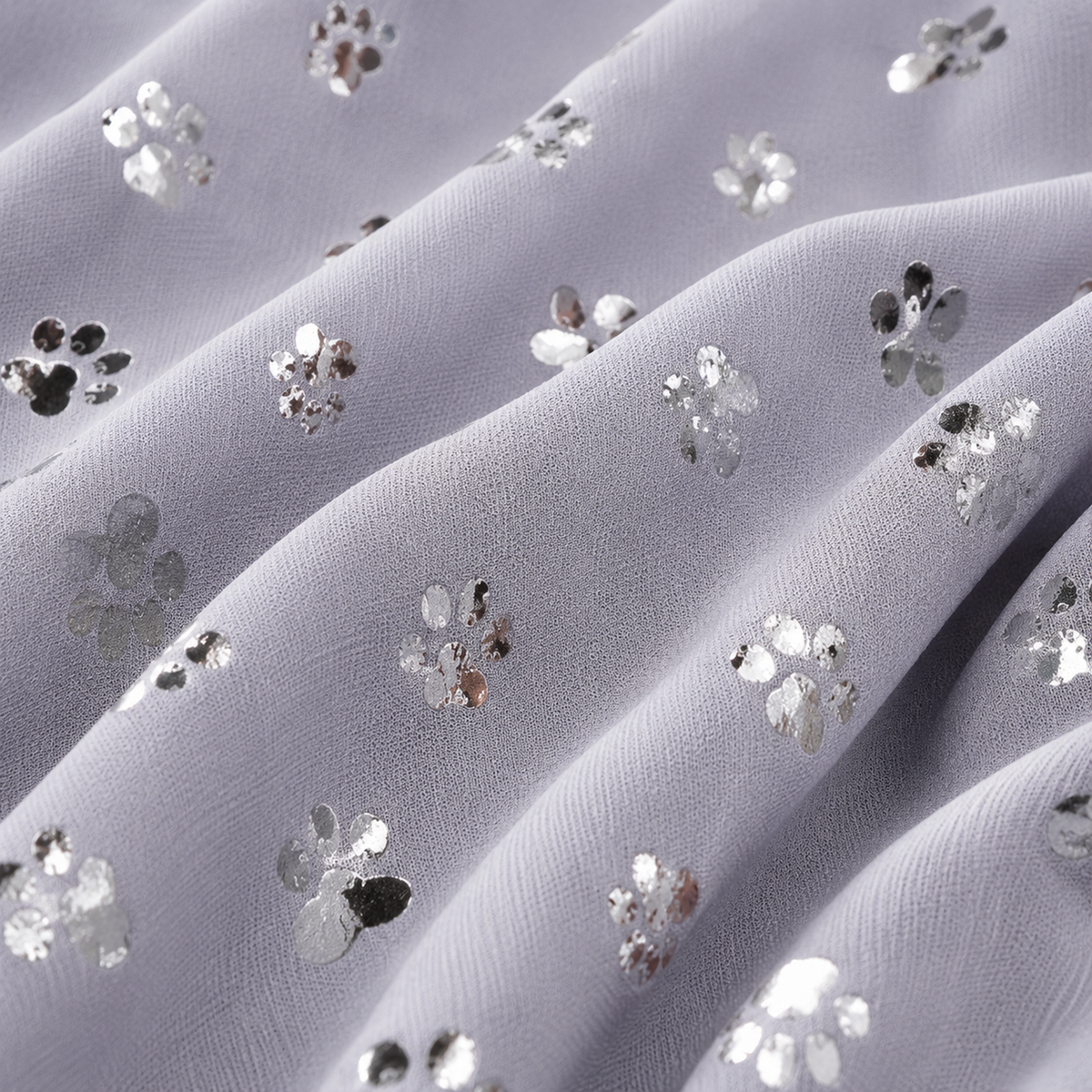 A close-up of sheer lavender-gray fabric with scattered silver sequin floral motifs and paw print embellishments.