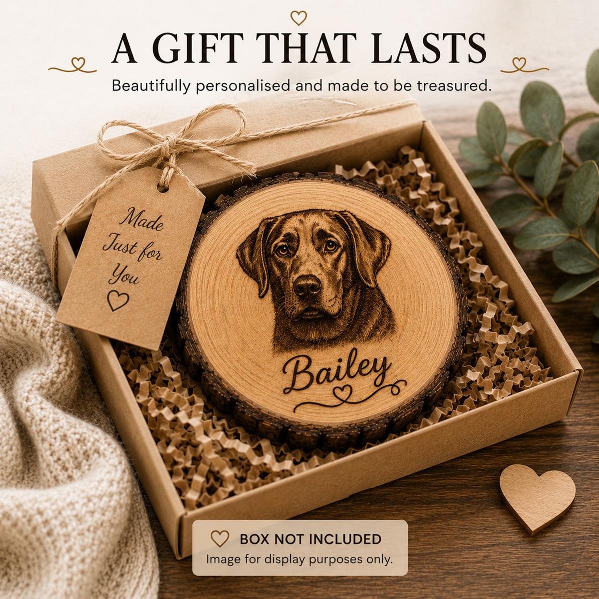 A personalised wooden dog memorial plaque engraved with a dog portrait and the name 'Bailey,' presented in a kraft gift box with shredded paper filler. Text at the top reads 'A GIFT THAT LASTS,' and a note at the bottom says 'BOX NOT INCLUDED' because the image is for display purposes only.