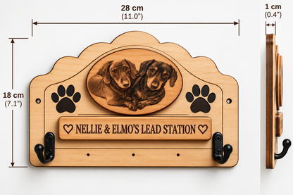 Personalised wooden dog lead rack with two black metal hooks, paw prints, and an oval dog portrait. The front plaque reads “NELLIE & ELMO’S LEAD STATION.