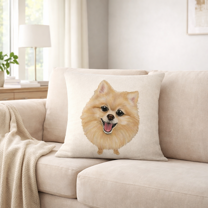 A square cream throw pillow featuring a printed illustration of a fluffy golden Pomeranian dog, resting on a beige fabric sofa in a bright, modern living room.