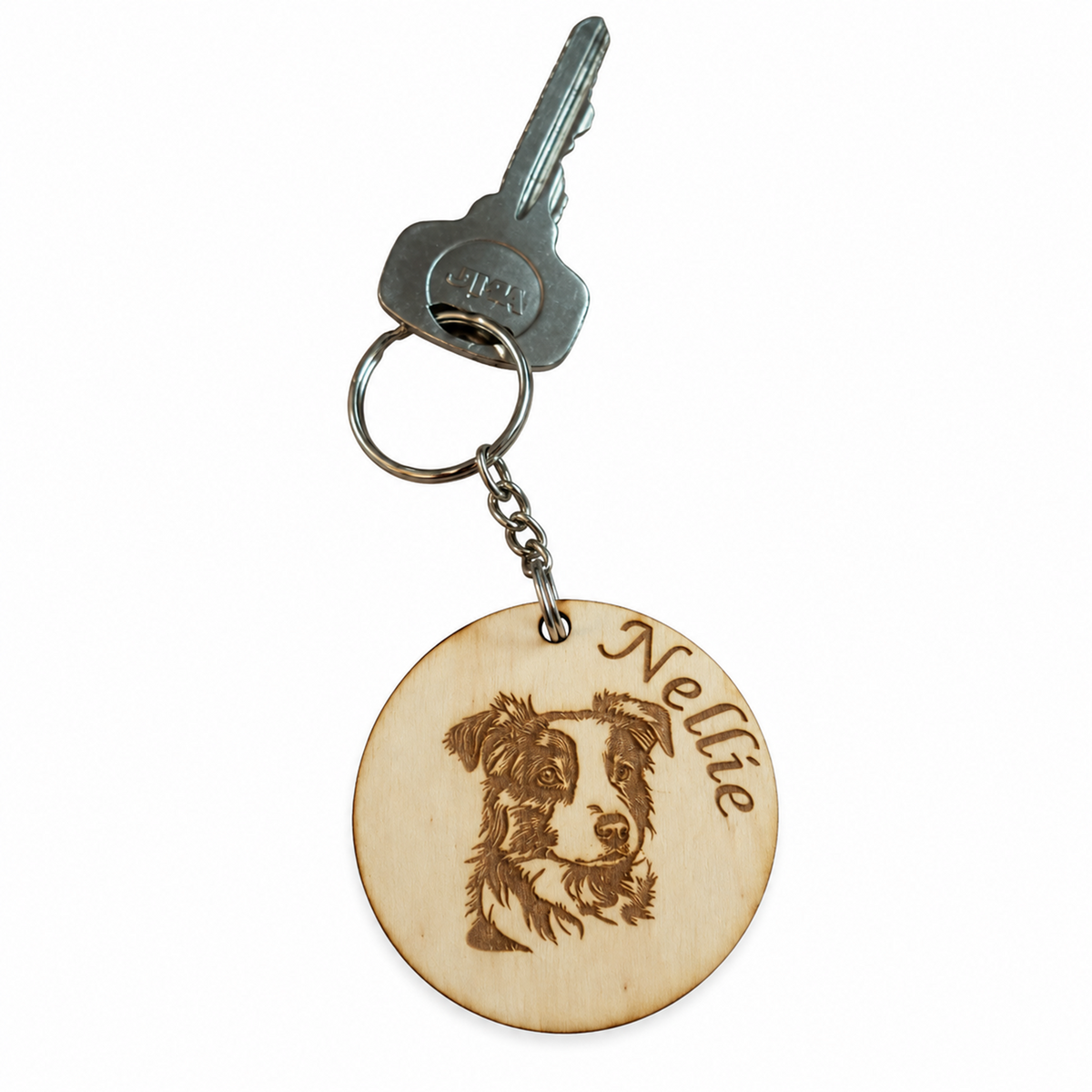 A personalised wooden round keychain featuring a laser-engraved portrait of a dog and the name 'Nellie', attached to a metal keyring with a key on a plain white background.
