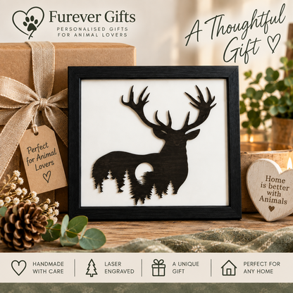 A framed laser-engraved wooden deer silhouette gift with a forest and moon design, displayed on a wooden surface with a wrapped gift box, pinecone, greenery, and decorative text overlays from Forever Gifts.