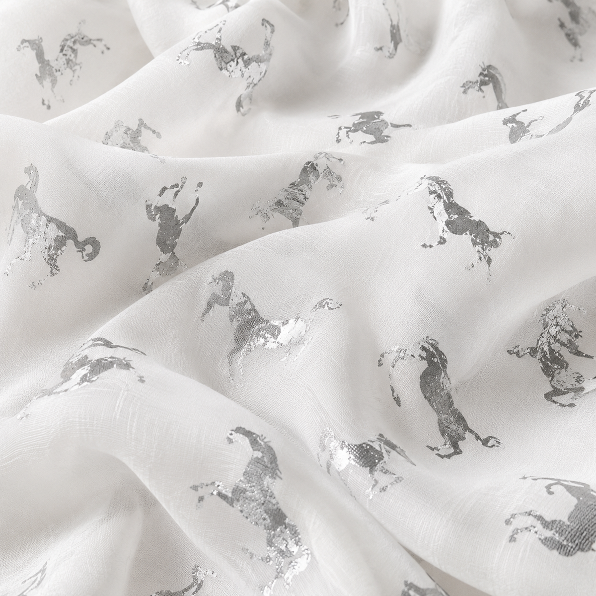 White scarf with a repeating metallic silver unicorn pattern, shown in soft folds.