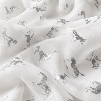 White scarf with a repeating metallic silver unicorn pattern, shown in soft folds.
