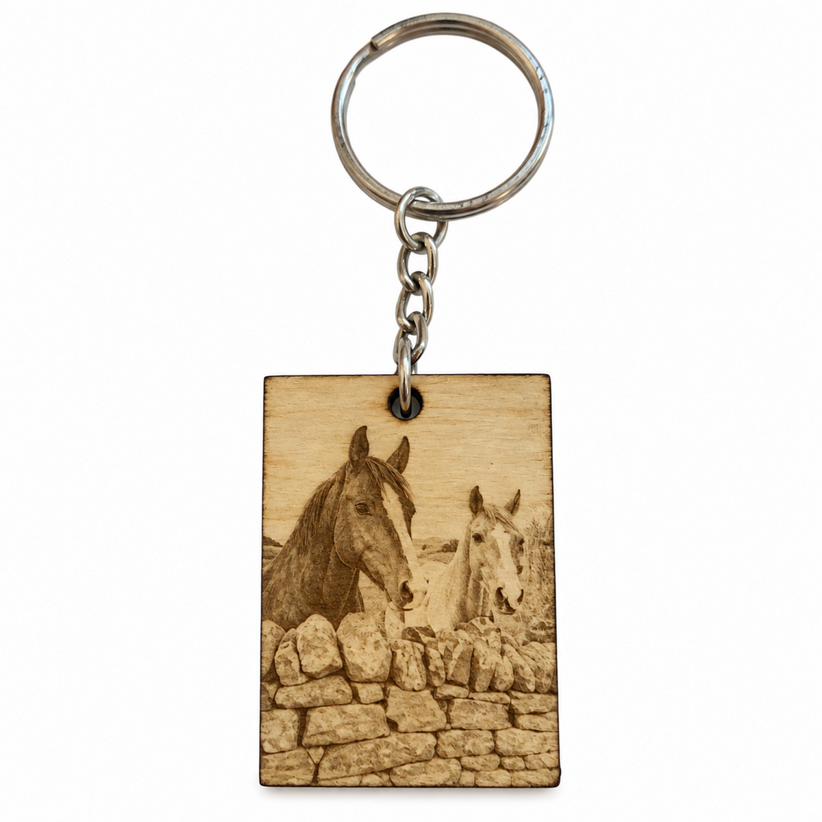 A rectangular wooden keychain with a laser-engraved image of two horses behind a stone wall, attached to a silver metal split ring and chain, on a plain white background.