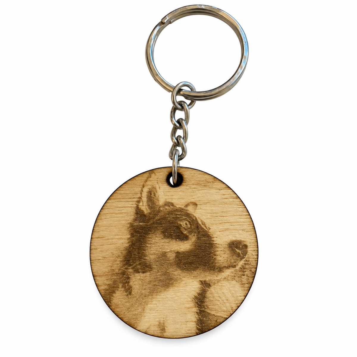 A round wooden keychain featuring a laser-engraved portrait of a dog, attached to a silver metal split ring and chain, shown on a plain white background.