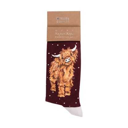 A single bamboo sock from Wrendale Designs, featuring a brown highland cow design on a dark maroon background with white stars, attached to a brown kraft paper header card.