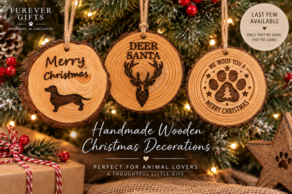 Three engraved wooden Christmas ornaments hang on a decorated Christmas tree. The round wood slices show black engravings: a dachshund with 'Merry Christmas', a deer head with 'DEER SANTA', and a paw print with 'WE WOOF YOU & MERRY CHRISTMAS'.