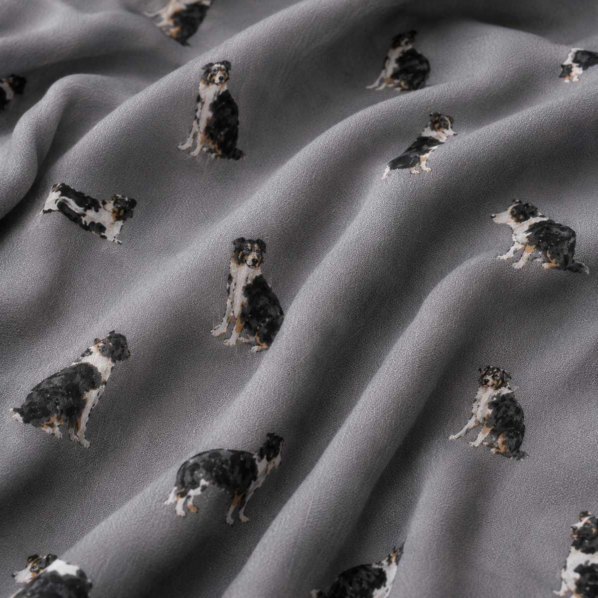 Grey scarf with a repeating print of black, white, and tan Border Collie dogs, shown in soft folds.
