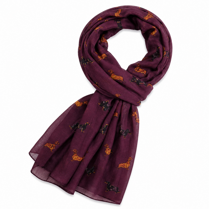 A burgundy scarf with a repeating pattern of small black and tan dachshund dogs, shown on a plain white background.