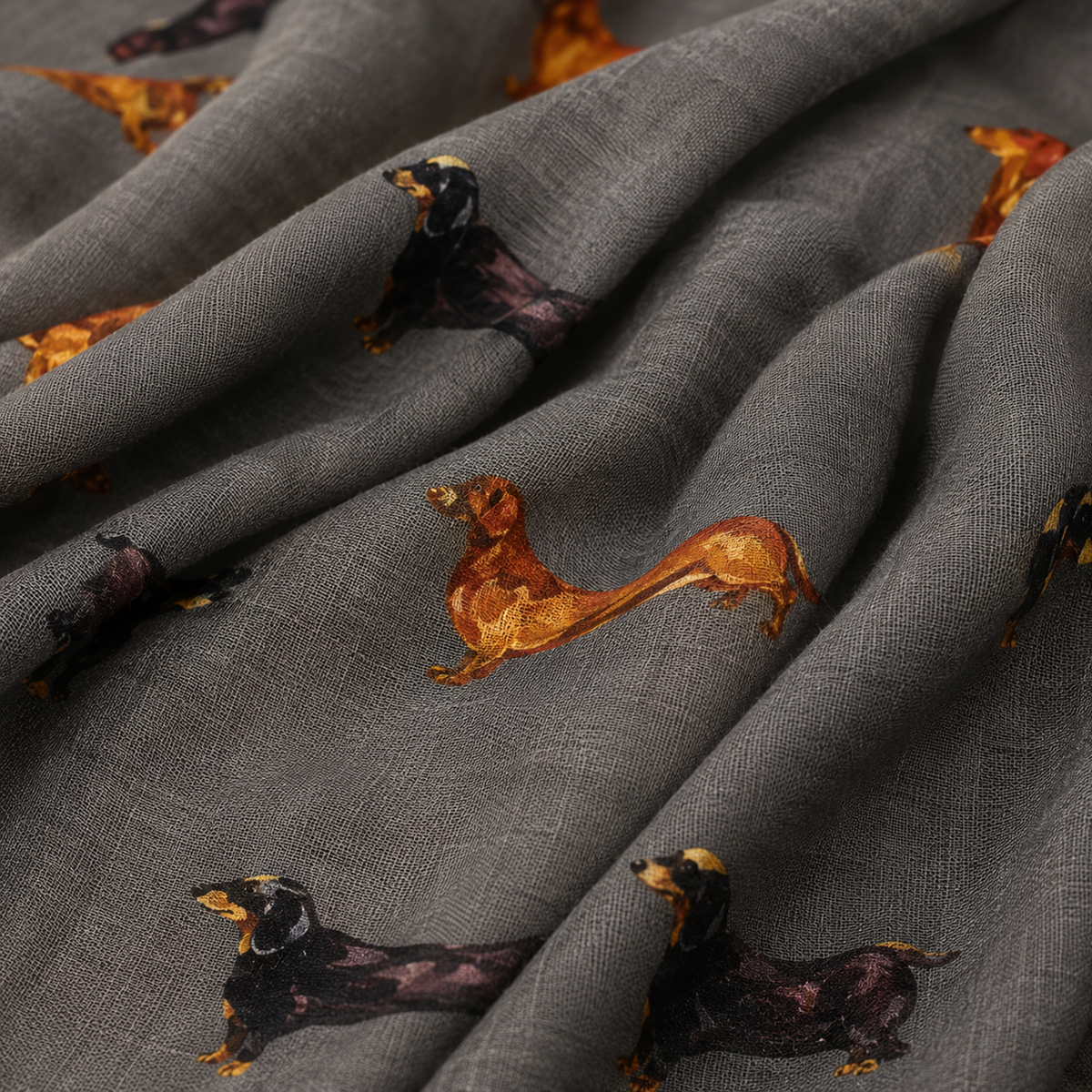 A close-up of draped grey scarf printed with dachshund dogs in black and tan.