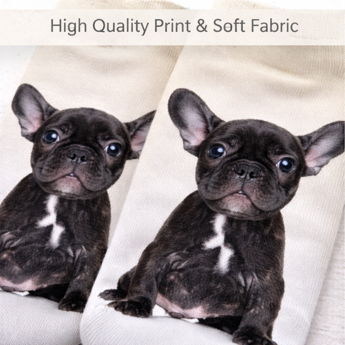 A close-up of a pair of off-white knit socks printed with two black French bulldog puppies, with a text banner at the top reading 'High Quality Print & Soft Fabric'.