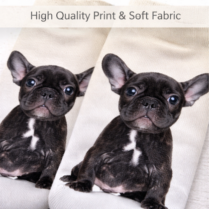 A close-up of a pair of off-white knit socks printed with two black French bulldog puppies, with a text banner at the top reading 'High Quality Print & Soft Fabric'.