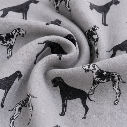 A close-up of light grey scarf with a repeating black Great Dane dog print, shown in soft folds to highlight the material texture and pattern.