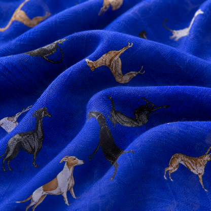A close-up of a vibrant royal blue fabric with a printed pattern of greyhounds in black, brown, and white, draped in soft folds.