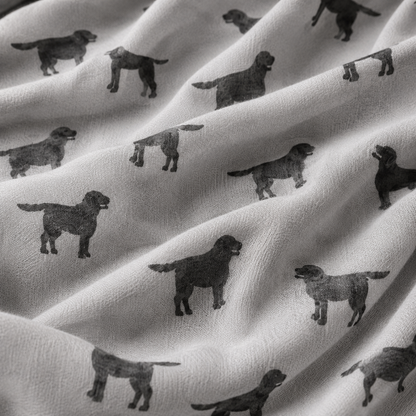A close-up of draped grey scarf printed with repeating black Labrador dog silhouettes, showing the soft texture and pattern detail.