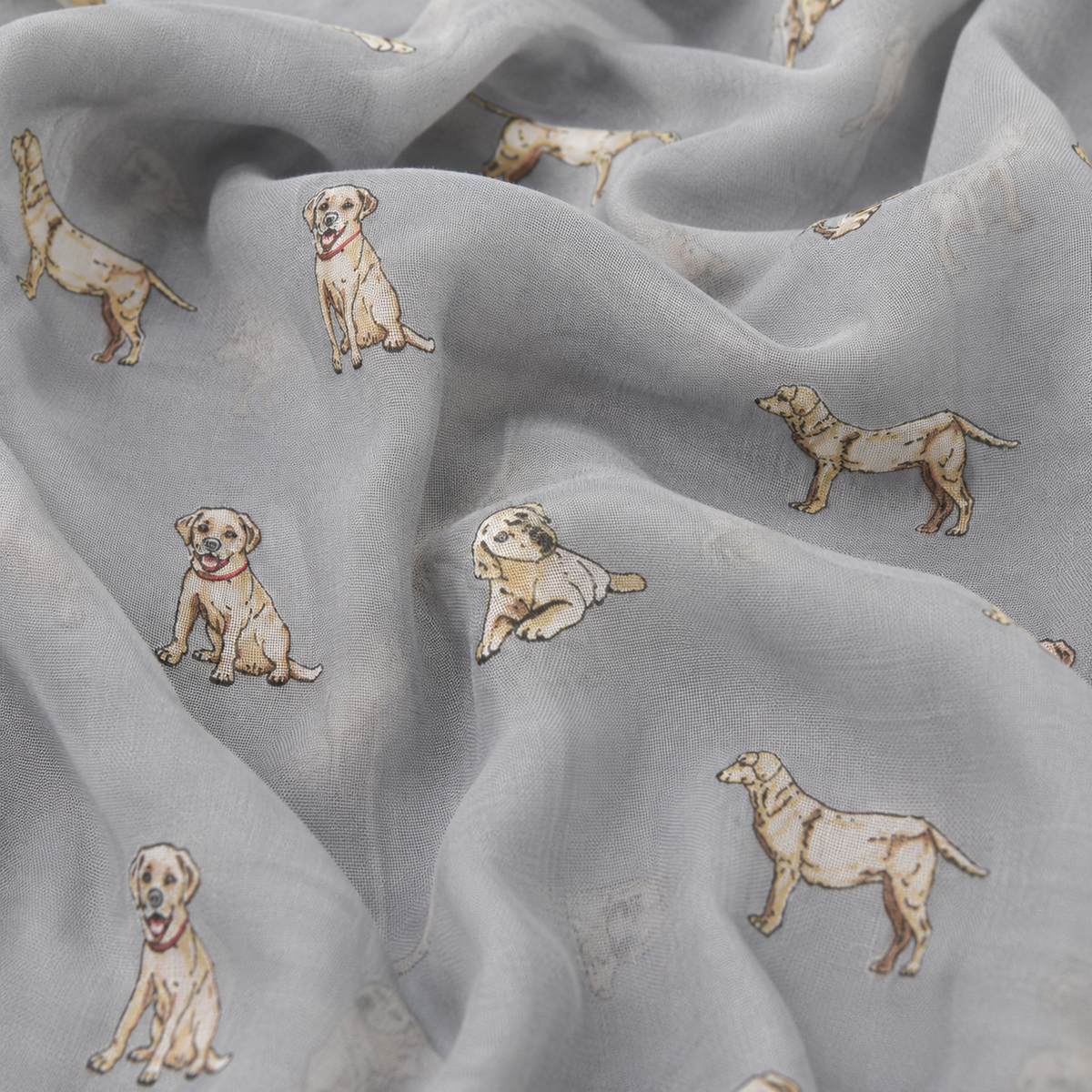Light grey scarf with a repeating print of Labrador retriever dog illustrations in beige, cream, and brown tones, shown in soft folds.