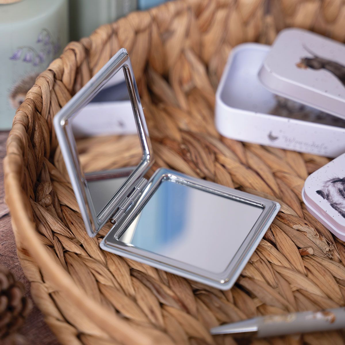 Compact mirror with a silver frame on a woven surface