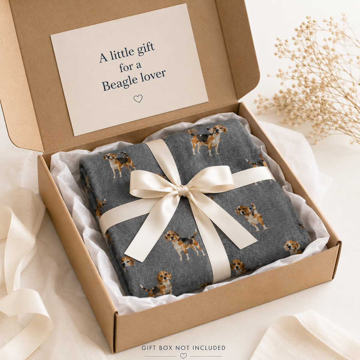 A folded grey scarf item with a Beagle dog print pattern, wrapped in a cream satin ribbon and presented inside a brown gift box with a handwritten note in the lid reading 'A little gift for a Beagle lover'.