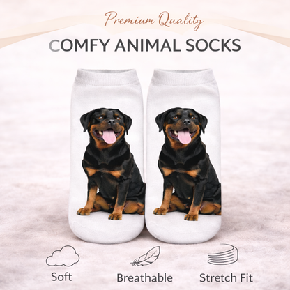 A pair of white ankle socks featuring printed images of a Rottweiler dog, displayed on a light beige background with promotional text and feature icons.