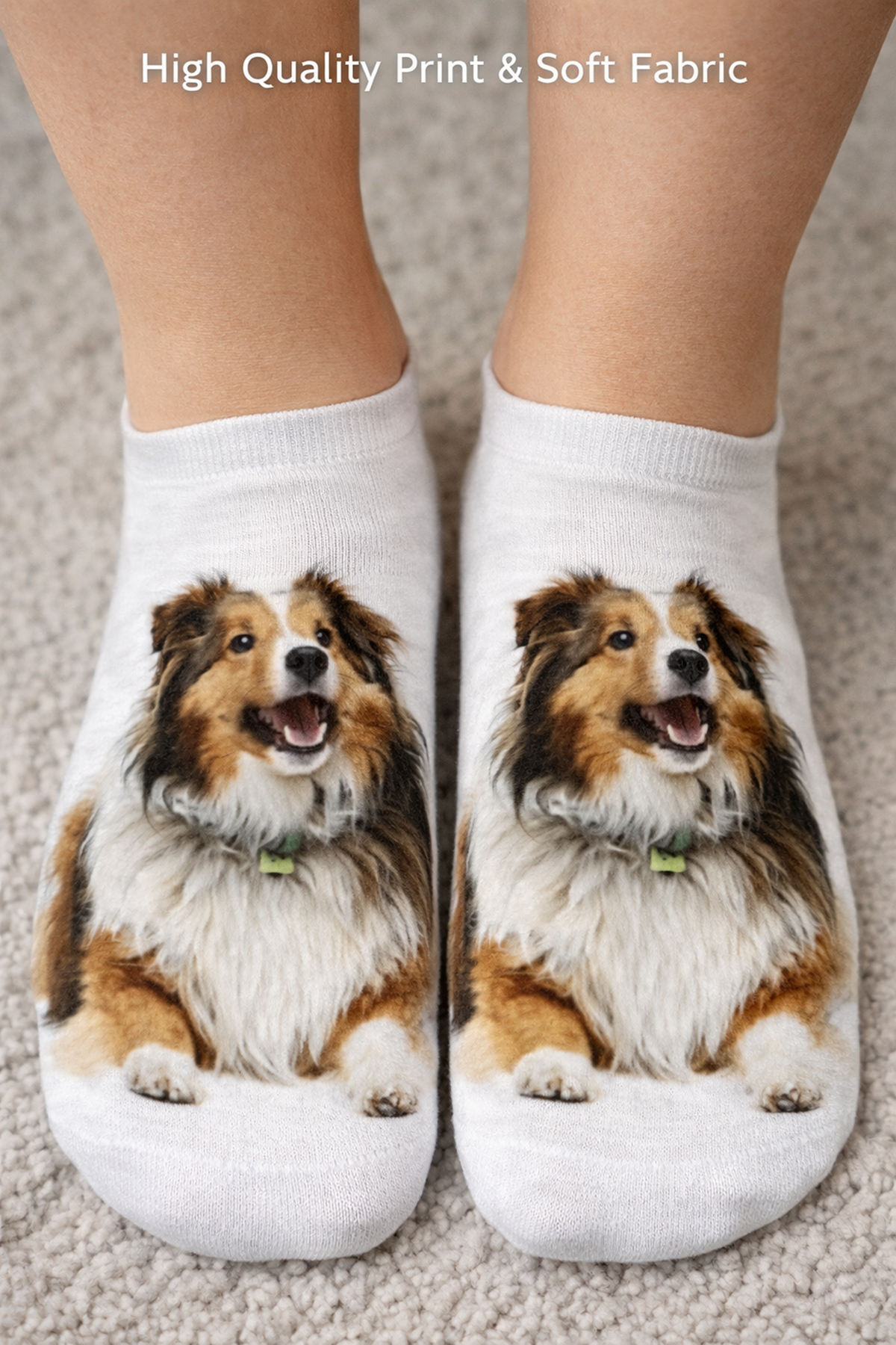 A pair of white ankle socks worn on feet, featuring a printed image of a smiling Sheltie dog on each sock. The background is a beige carpet, with text at the top reading 'High Quality Print & Soft Fabric'.
