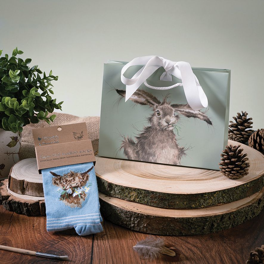 Gift bag with rabbit design and matching socks on a wooden surface with decorative elements.