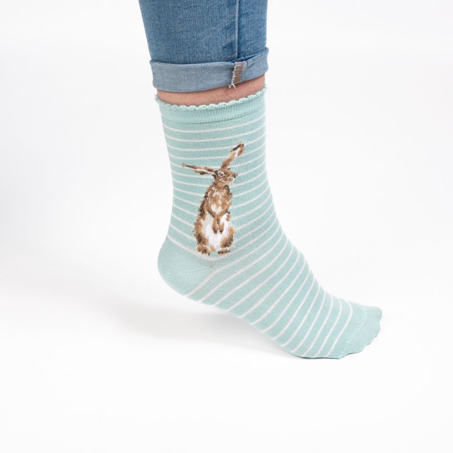 Light blue striped sock with a rabbit design worn by a person on a white background