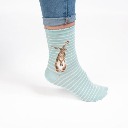 Light blue striped sock with a rabbit design worn by a person on a white background